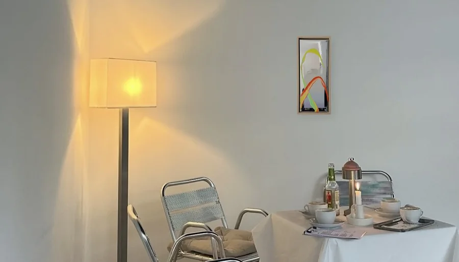 A styled room with a floor lamp, a set table and a framed WAVES OF LIFE painting on the wall